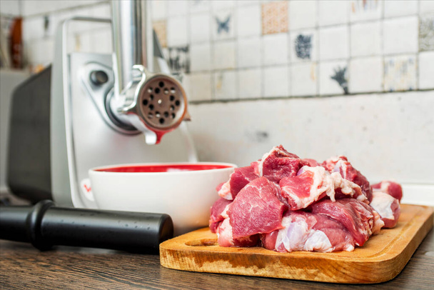 Macinino di carne con carne fresca su un tagliere in interno di cucina. Macchina per tritare la carne in carne macinata. - Foto, immagini