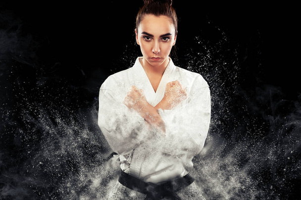 Portrait of sporty karate and taekwondo woman in white kimono with black belt on dark background. - Fotoğraf, Görsel