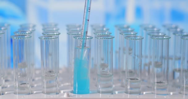 In een laboratorium analyseert een wetenschapper met een pipet een gekleurde vloeistof om het DNA en de moleculen in de reageerbuizen te extraheren. Onderwerp: onderzoek, biochemie, natuur, farmaceutische geneeskunde - Video