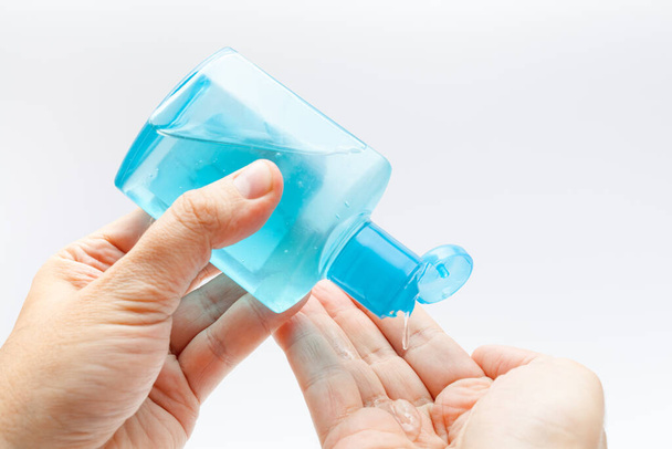 Ιός της Κορόνας έννοια απολύμανσης: Αρσενικό χέρι που κρατά μπουκάλι απολυμαντικό και ρίχνει απολυμαντικό τζελ αλκοόλ στην παλάμη του άλλου χεριού για την πρόληψη covid-19. Καθαρισμός χεριών για την πρόληψη από το coronavirus.  - Φωτογραφία, εικόνα