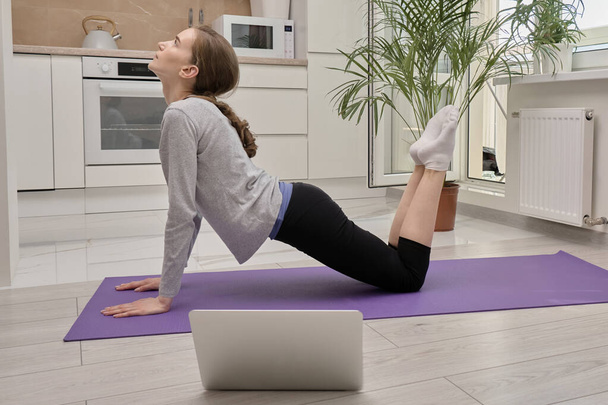 A blonde woman does sports at home on a yoga Mat. - Photo, Image
