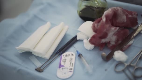 手術中の医療テーブルの上の血だらけの包帯.行動だ。手術室の青い布の上に横たわる医療器具の終わり、薬の概念. - 映像、動画