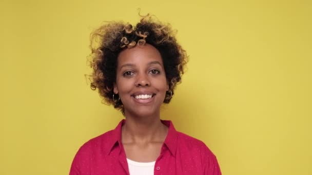 Young african woman with curly hair smiling standing on colored wall. - Imágenes, Vídeo