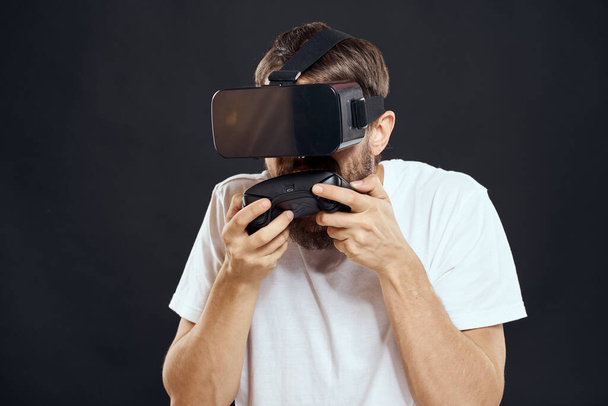 man wearing virtual reality glasses with gamepad in hand technology games leisure dark background - Photo, Image