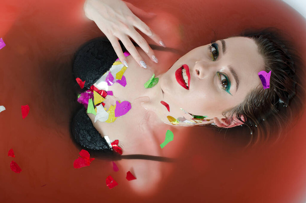 girl with bright makeup in a bath with red water. - Foto, Bild