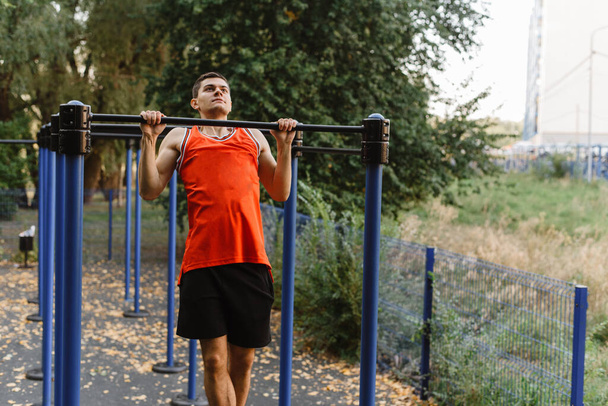 Muskulöser, hemdsloser Mann beim Hochziehen am Reck im Freien. Sportbanner, Kopierraum, Fitness-Motivation - Foto, Bild
