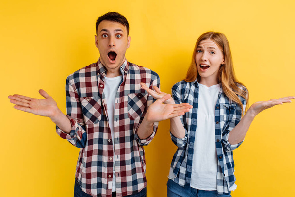 Shocked excited young couple, man and woman on yellow background - Photo, image