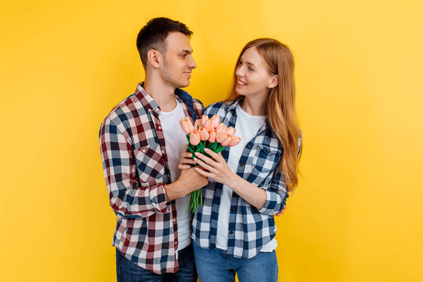 romantic couple, man and woman with a bouquet of flowers, on a yellow background, Valentine's Day - Фото, зображення