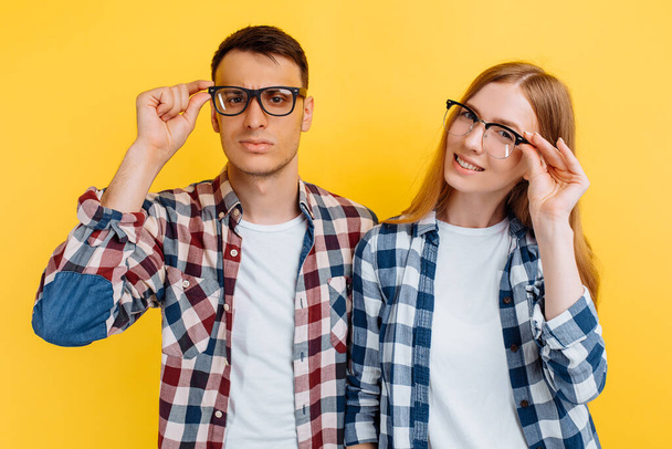 Happy young students, man and woman wearing glasses for vision on yellow background - Foto, Bild
