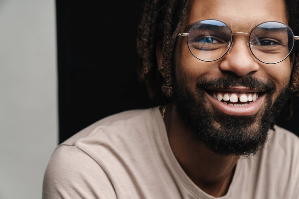 Image of african happy guy posing isolated over black and white wall background in eyeglasses - 写真・画像