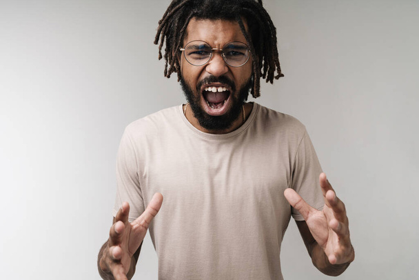 Image of screaming stressed african guy isolated over grey wall background in eyeglasses - Zdjęcie, obraz
