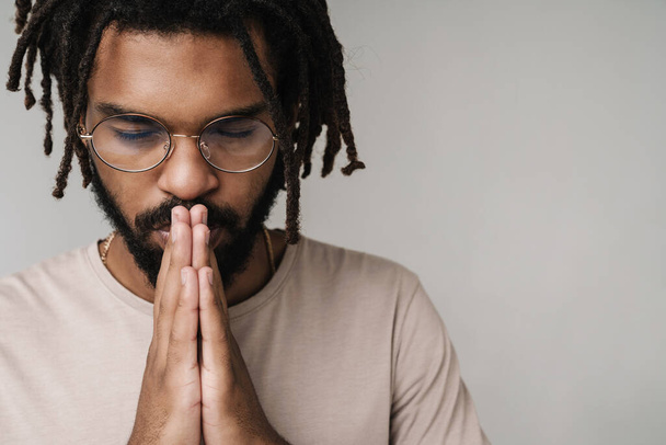 Image of serious praying african guy isolated over grey wall background in eyeglasses - Fotografie, Obrázek