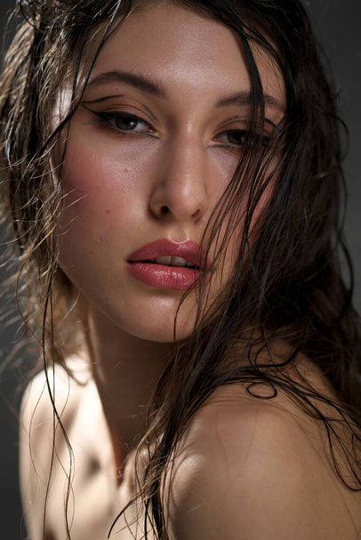 The face of a beautiful young girl with wet black hair close-up. Eastern appearance. Nude makeup, natural skin. - Фото, изображение
