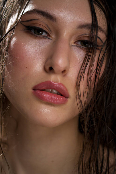 The face of a beautiful young girl with wet black hair close-up. Eastern appearance. Nude makeup, natural skin. - Фото, зображення