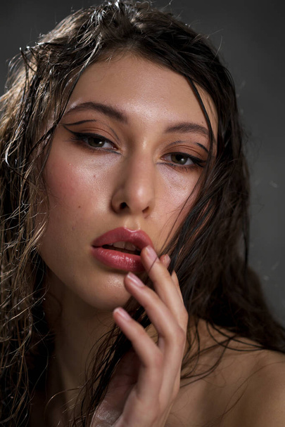 The face of a beautiful young girl with wet black hair close-up. Eastern appearance. Nude makeup, natural skin. - Photo, Image