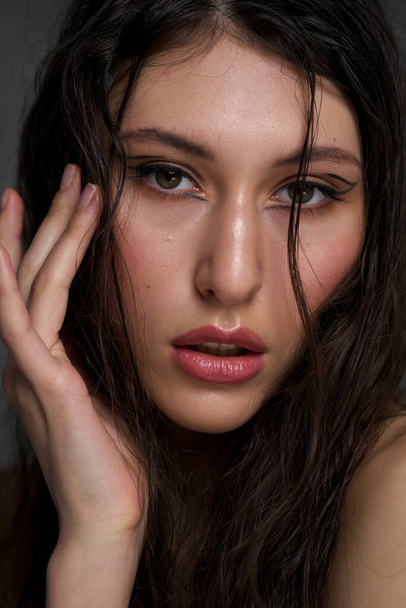 The face of a beautiful young girl with wet black hair close-up. Eastern appearance. Nude makeup, natural skin. - Foto, immagini