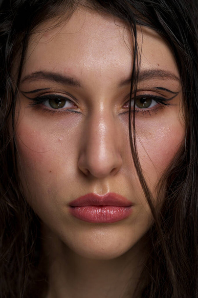 The face of a beautiful young girl with wet black hair close-up. Eastern appearance. Nude makeup, natural skin. - Foto, immagini