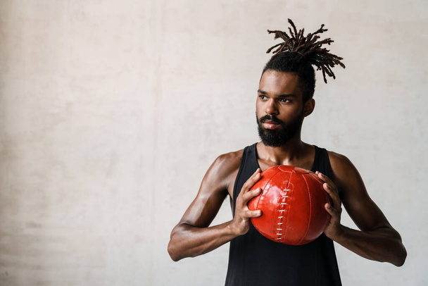 Image of athletic african american sportsman working out with medicine ball indoors - Foto, immagini