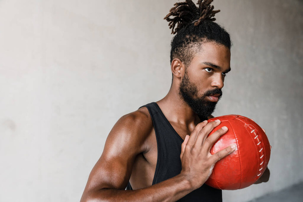 Beeld van atletische Afrikaanse Amerikaanse sportman uit te werken met medicijnbal binnen - Foto, afbeelding