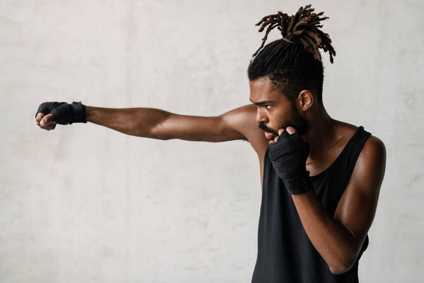 Image of athletic african american sportsman boxing while working out indoors - Foto, Imagem