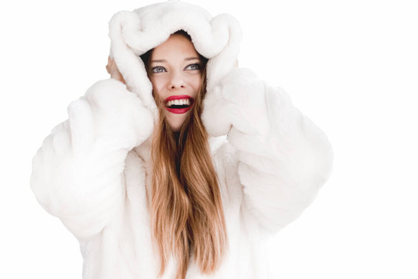Jonge vrouw in pluizig bont jas met capuchon wrap, warme winterkleding voor mode en kerstvakantie - Foto, afbeelding