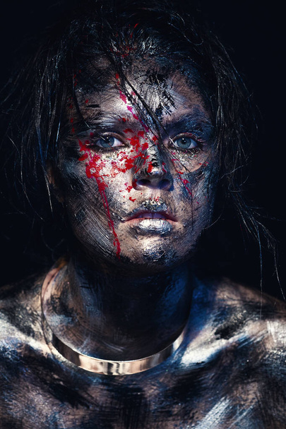 Fashion glamour portrait of a beautiful young caucasian woman on a black background. Creative makeup. Dramatic dark image. The effect of a dirty face with drops of blood, metal collar on the neck - Foto, immagini