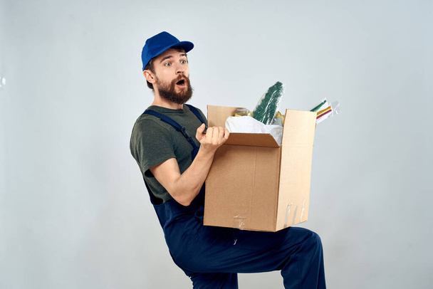 Hombre en uniforme de trabajo con cajas en manos entrega estilo de vida de carga - Foto, Imagen