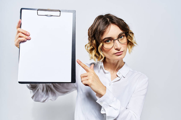 Donna d'affari con una cartella di documenti bianchi in mano su uno sfondo chiaro e modello di occhiali per acconciatura - Foto, immagini