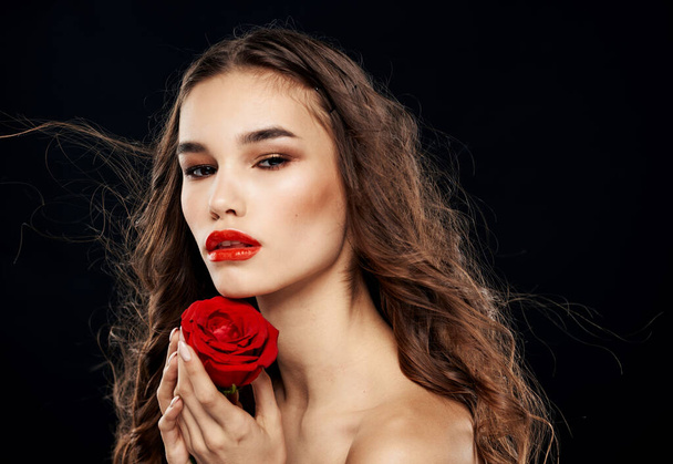 Mujer encantadora con rosa roja sombra de ojos brillante maquillaje fondo negro - Foto, imagen