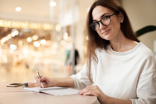 Young businesswoman in eyeglasses planning and writing down the daily schedule in agenda. Time management and calendar reminder event for planner concept. Planning appointment and meetings. - Фото, зображення