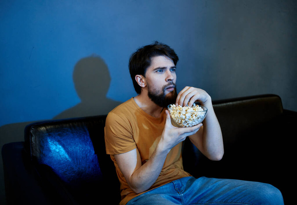 самотній чоловік сидить на дивані з попкорнськими тарілками сіра стіна
 - Фото, зображення