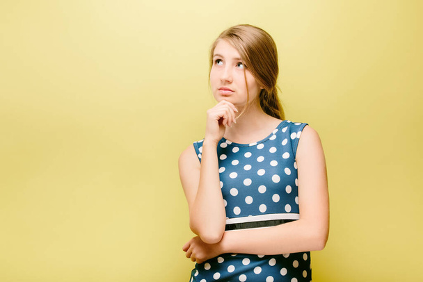 teen girl on yellow background decides what choose - Foto, imagen