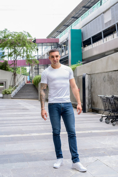 Full body shot of handsome man with tattoos in the city - Photo, Image