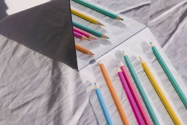 Πολύχρωμο μολύβι σε μια σειρά αντανάκλασης στον καθρέφτη στο τραπέζι. - Φωτογραφία, εικόνα