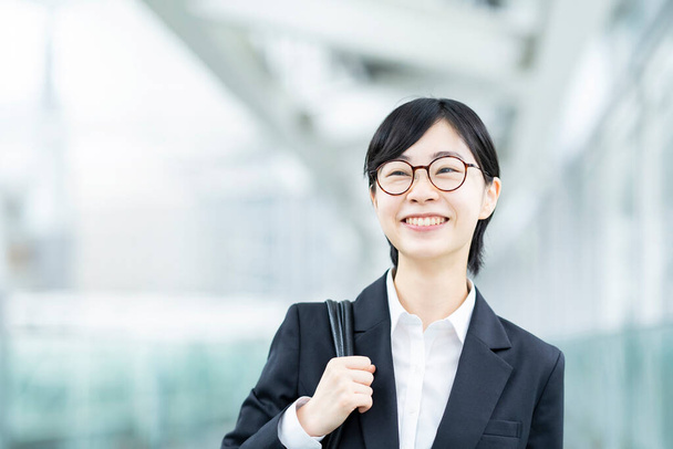 Aziatisch jong vrouw in een pak en bril met glimlach - Foto, afbeelding