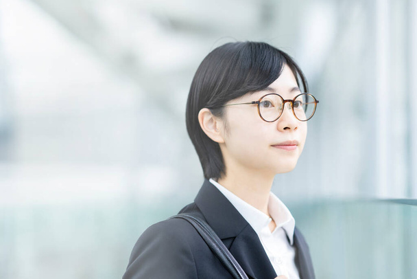Asiatique jeune femme dans un costume et des lunettes avec sourire - Photo, image
