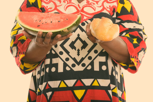 スタジオショットの脂肪黒アフリカの女性保持パンとスイカのスライス - 写真・画像