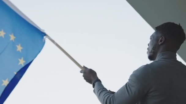 Nuori viehättävä musta mies heiluttaa Euroopan unionin lippua - Materiaali, video