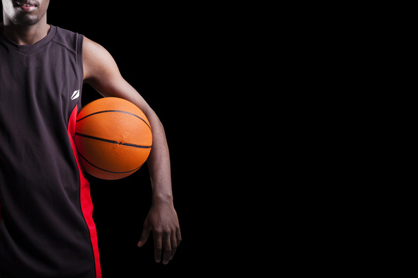 Imagen de un jugador de baloncesto sosteniendo una pelota contra el backgro oscuro
 - Foto, Imagen