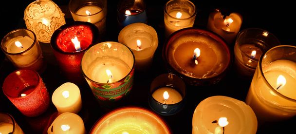 Muchas velas de diferentes tamaños y estilos en la oscuridad - Foto, imagen