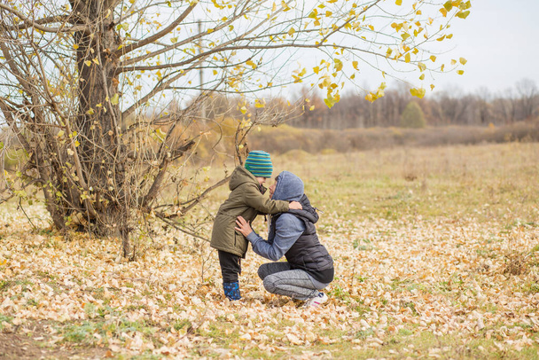 Grandmother hugging litlle grandson outdoor in autumn forest  - Photo, Image