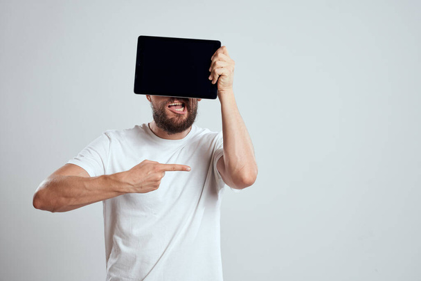 emotionele man met een tablet voor zijn ogen gebaren met zijn handen bijgesneden uitzicht Copy Space Model lichte achtergrond - Foto, afbeelding