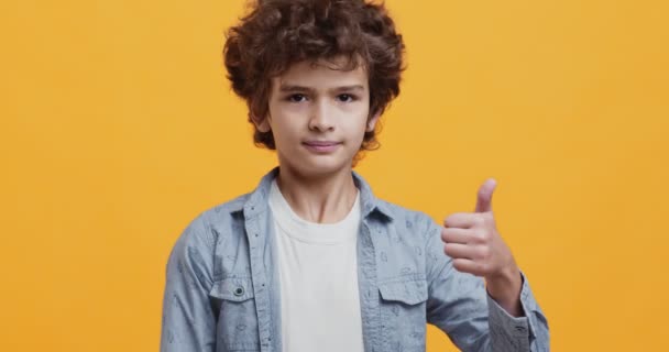 Children approval. Adorable curly little boy nodding head and showing thumb up gesture, agreement and like concept - Footage, Video