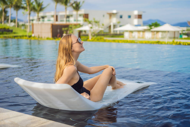 Beautiful Girl Relaxing by the Pool at Tropical Resort - 写真・画像