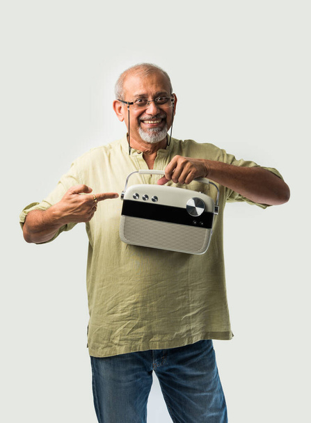 Indiai ázsiai idős férfi vagy férfi idősebb felnőtt zenét hallgatni vintage rádió segítségével fejhallgató és tánc, elszigetelt fehér háttér - Fotó, kép
