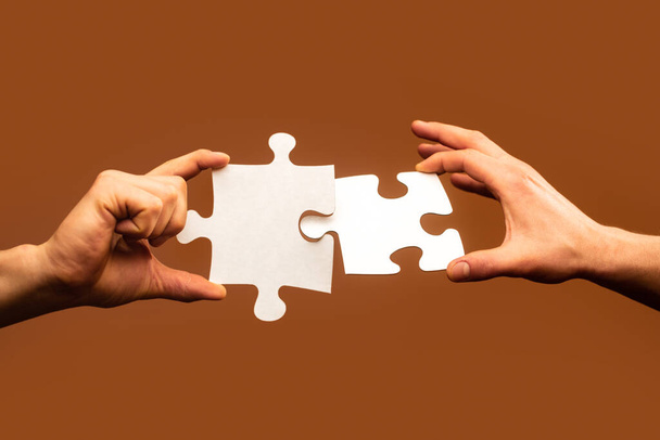 Two hands trying to connect couple puzzle. Businessman hand connecting jigsaw puzzle. Closeup hands of man connecting jigsaw puzzle. Business solutions, success and strategy concept - Photo, Image