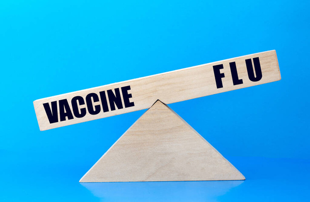 concept of the balance of words vaccine and flu on wooden scales - Zdjęcie, obraz