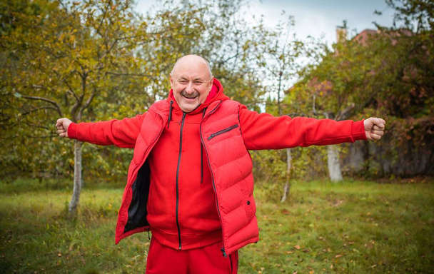 Старший мужчина в красной спортивной одежде, мужчина на пенсии, образ жизни пожилых людей - Фото, изображение
