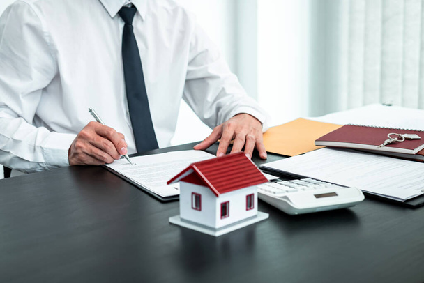 Agent immobilier document d'entente de travail contrat d'assurance habitation approuvant les achats pour le client avec modèle de maison et clé sur la table. - Photo, image
