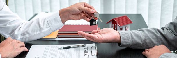 Агент з нерухомості представляє домашній кредит і дає ключі клієнту після підписання контракту на оренду будинку з затвердженою заявою на страхування майна
. - Фото, зображення